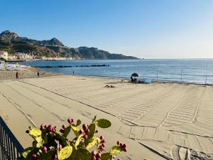 einen Strand mit Menschen auf Sand und Wasser in der Unterkunft White Pearl - Luxury in Giardini-Naxos