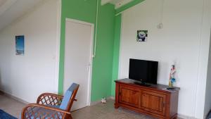 a living room with a tv on a wooden dresser at Maison du soleil in Les Abymes