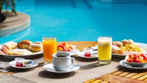 una mesa con platos de comida y dos vasos de zumo de naranja en LP Los Portales Hotel Piura, en Piura
