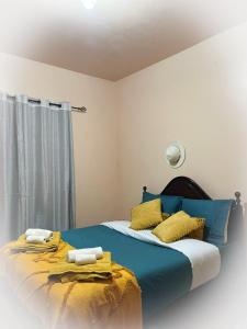 een slaapkamer met een blauw bed met gele kussens bij Home Thomas in Lombada dos Marinheiros