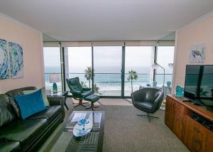 a living room with a couch and chairs and a television at Capri Beach Accommodations at Capri By The Sea in San Diego