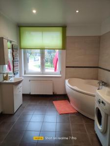 een badkamer met een bad, een wastafel en een raam bij Senlejas Apartamenti in Ogre