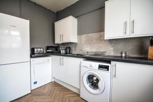 a kitchen with white cabinets and a washer and dryer at The Good night rooms liverpool 