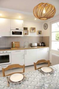 une cuisine avec des placards blancs et une table avec des chaises dans l'établissement Paddock Prestige by La Boîte En Plus, à Chantilly