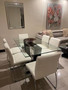 uma sala de jantar com uma mesa de vidro e cadeiras brancas em Departamento en brasil no Rio de Janeiro