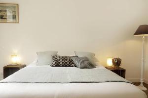 - un lit blanc avec des oreillers au-dessus dans l'établissement Paddock Prestige by La Boîte En Plus, à Chantilly