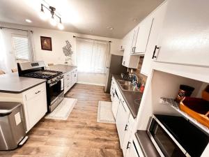 uma cozinha com armários brancos e electrodomésticos de aço inoxidável em New HB Family Vacation Home em Midway City