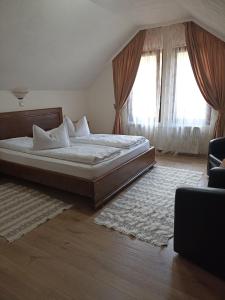 a bedroom with a large bed and two windows at Pensiunea Sofy in Arieşeni