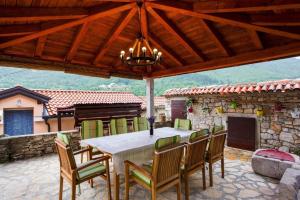 a dining table and chairs on a patio with a fireplace at House Golovik in Brseč