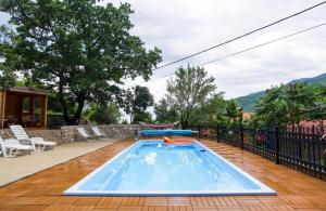 a swimming pool on a wooden deck with a fence at House Golovik in Brseč