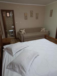 a bedroom with a white bed and a couch at Pensiunea Sofy in Arieşeni