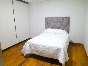 - une chambre avec un lit blanc et une tête de lit gris dans l'établissement Apartamento Luz de Luna1, à La Paz