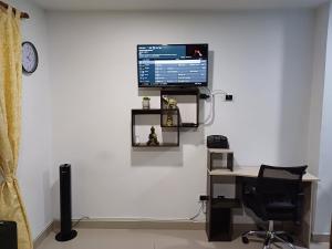 Habitación con escritorio y TV en la pared. en Apartamento Ángel Namaste en Bello