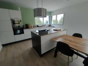 cocina con armarios blancos y mesa de madera en Maison de vacances 3 chambres, en Locquirec