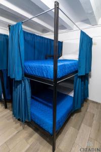 two bunk beds in a room with blue sheets at Hotel Citadin in Guatemala