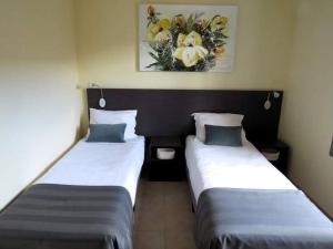 French Country Villas في Les Forges: سريرين في غرفة الفندق مع ورود على الحائط