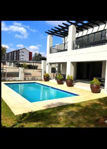 a house with a swimming pool in front of a building at Medon Luxury Suites with power back up Bryanston Sandton in Johannesburg