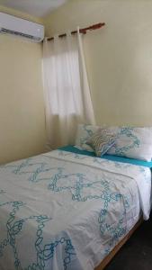 a bedroom with a bed with a white blanket and a window at Alojamiento Familiar Pedernales. in Pedernales