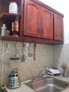 a kitchen with a sink and wooden cabinets and utensils at Alojamiento Familiar Pedernales. in Pedernales