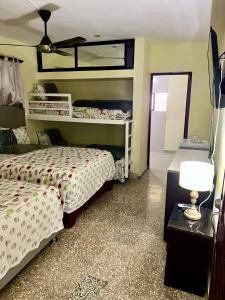 a bedroom with two beds and a table with a lamp at Hotel Maria Bonita Higüey in Higuey