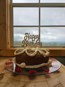 um bolo de aniversário sentado numa mesa em frente a uma janela em Chasing Views Tiny House em Dandridge