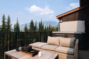 a patio with a couch and a table on a balcony at New! Luxury, Top Floor, Ski in/Ski Out, Private Hot Tub and Mountain Views in Sun Peaks