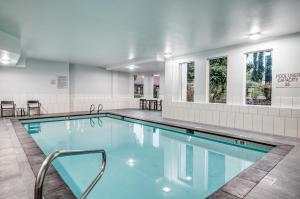 uma piscina com mesas, cadeiras e janelas em Staybridge Suites Federal Way - Seattle South , an IHG Hotel em Federal Way