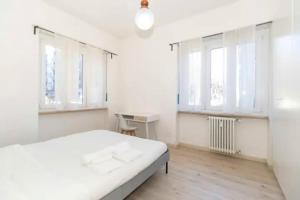 a white bedroom with a bed and two windows at city flat [strategic position] in Turin