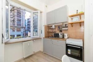 una pequeña cocina con armarios blancos y una ventana en city flat [strategic position] en Turín