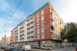 un bâtiment en briques rouges avec des voitures garées devant lui dans l'établissement city flat [strategic position], à Turin