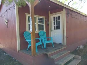 dos sillas sentadas en el porche de una casa pequeña en The Butterfly Cabin with adjustable king-size bed. en Kempner