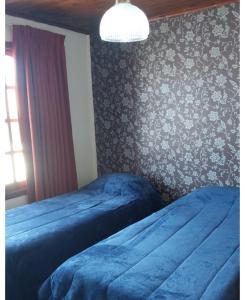 um quarto com 2 camas com lençóis azuis e uma parede em Hospedaje compartido SOL em Ushuaia