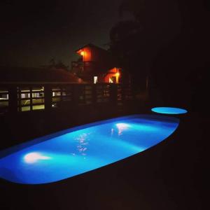 a blue swimming pool at night with a house in the background at Suite Farol do Arvoredo in Governador Celso Ramos