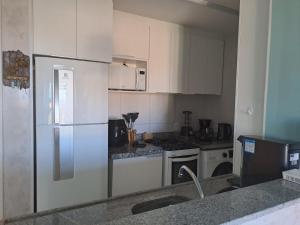 cocina con armarios blancos y nevera en VG Sun Cumbuco 406 en Cumbuco