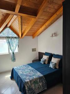 a bedroom with a blue bed with a wooden ceiling at Soleil Beach House in Santa Maria