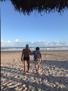 dos personas caminando por la playa en Casa pé na areia ao lado de Mangue Seco, en Jandaíra