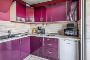 a kitchen with purple cabinets and a sink at Appartement Paroco - Welkeys in Cabourg +7 photos