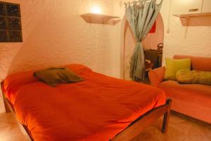 1 dormitorio con cama de color naranja y sofá en Casa Binah, en Cabo Polonio