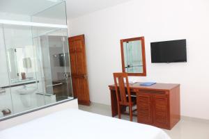 a bedroom with a desk and a shower and a television at Hoang Ngoc Hotel in Pleiku