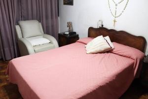 ein Schlafzimmer mit einem rosa Bett mit einem Stuhl und einem Stuhl in der Unterkunft Casa Royo de Ciudad in Mendoza