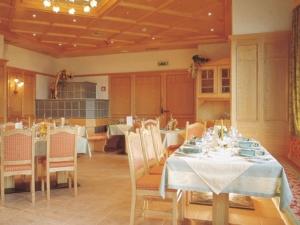 a dining room with tables and chairs and a kitchen at Gasthof Pitztaler Hof in Wenns