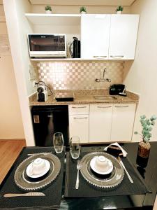 a kitchen with a table with plates and wine glasses at São Paulo Moema Times Square - Suite LUXO in Sao Paulo