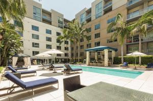 a pool with lounge chairs and umbrellas next to a building at Oasis in heart of Hollywood in Los Angeles