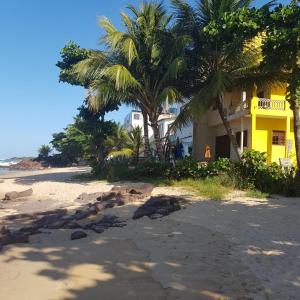 una casa amarilla en la playa con palmeras en Xareu-Balanço das Ondas! en Cabo de Santo Agostinho