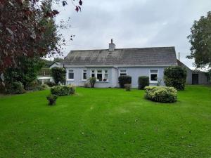a white house with a yard with green grass at Teachín na Siúire in Garnavilla