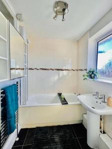 Baño blanco con bañera y lavamanos en Canvey Island Bliss By Artisan Stays I Free Parking I Sleeps 5 I Relocation or Business, en Canvey Island