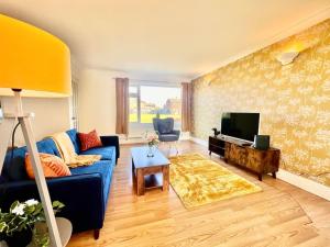 a living room with a blue couch and a television at Canvey Island Bliss By Artisan Stays I Bank Holiday Offer I Free Parking in Canvey Island