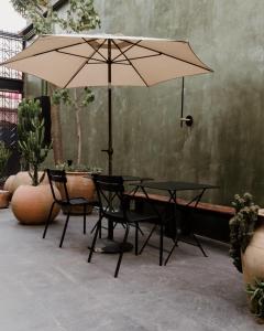 a table and chairs with an umbrella in a courtyard at Majagua Hotel Boutique -Adults Only in Oaxaca City