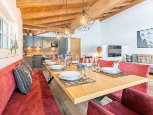 a dining room with a wooden table and red chairs at Chalet Aquila in Niedernsill