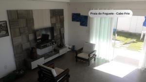 a living room with a tv and a chair at Praia do Foguete - Aluguel Econômico in Cabo Frio